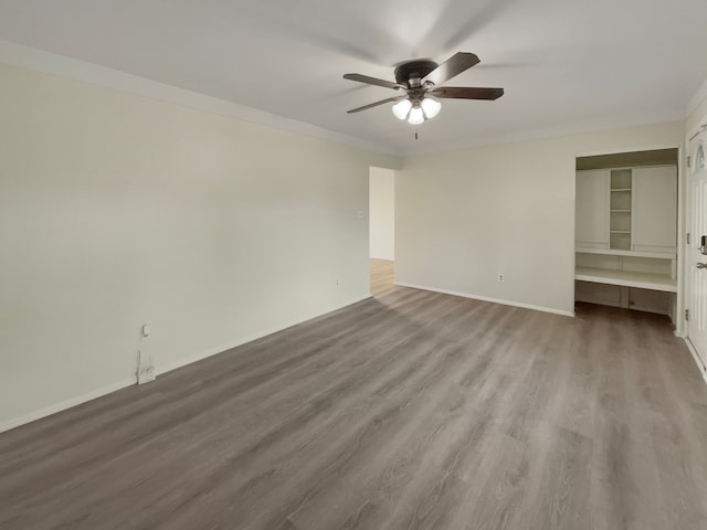 interior space with a ceiling fan, wood finished floors, a closet, crown molding, and baseboards