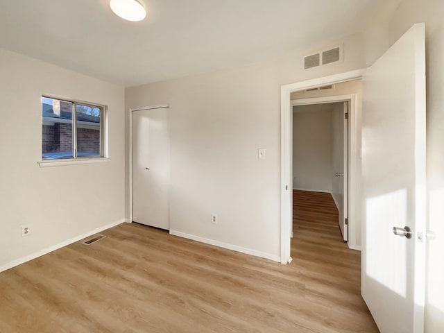 unfurnished bedroom featuring light wood finished floors, visible vents, a closet, and baseboards