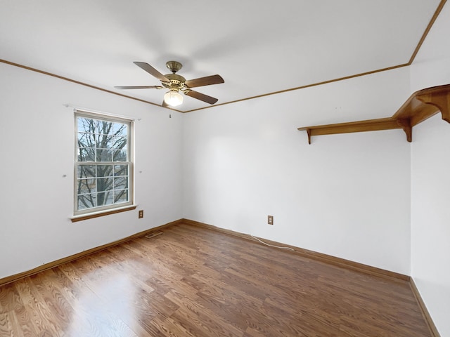 unfurnished room with visible vents, baseboards, ceiling fan, ornamental molding, and wood finished floors