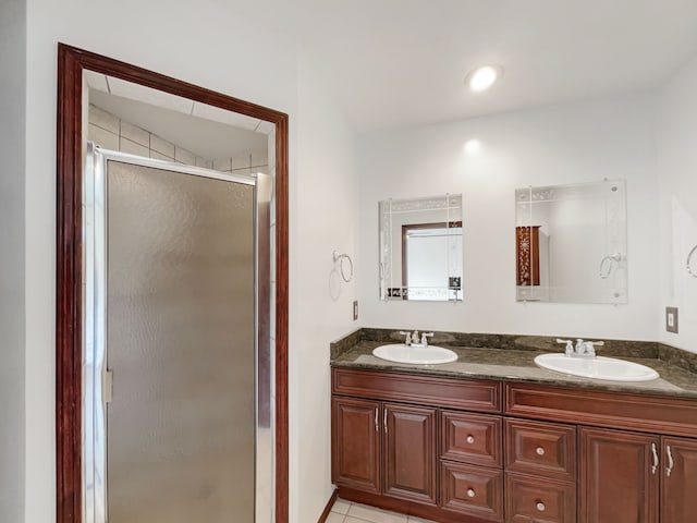 full bath with double vanity, a shower stall, and a sink