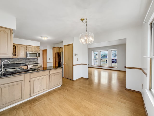 kitchen featuring light wood-style flooring, a sink, light brown cabinetry, stainless steel appliances, and tasteful backsplash