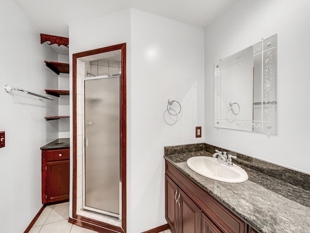 full bathroom with baseboards, vanity, a shower stall, and tile patterned flooring