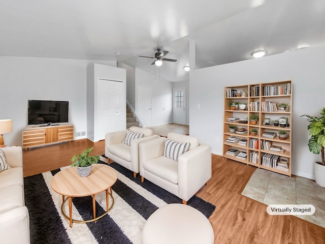 living room featuring visible vents, ceiling fan, baseboards, stairway, and light wood-type flooring