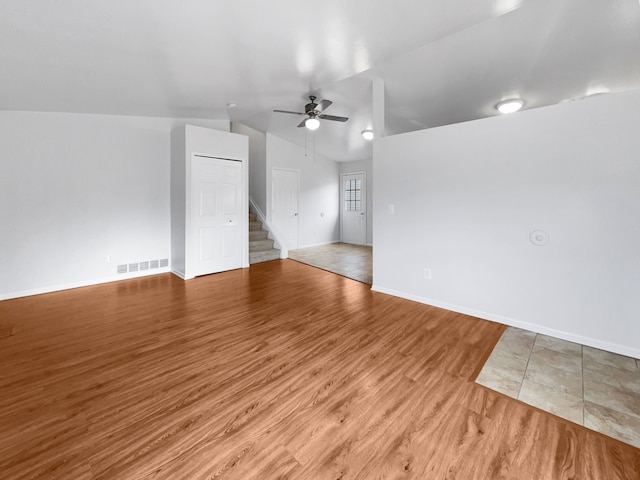 interior space with stairway, wood finished floors, visible vents, lofted ceiling, and ceiling fan