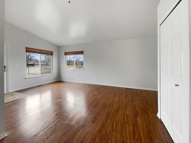 interior space with baseboards, lofted ceiling, and wood finished floors