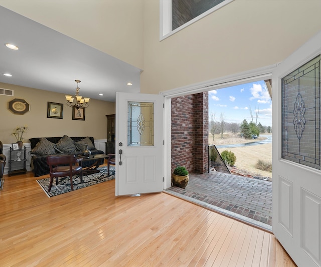 entrance foyer with recessed lighting, light wood-type flooring, a high ceiling, and an inviting chandelier