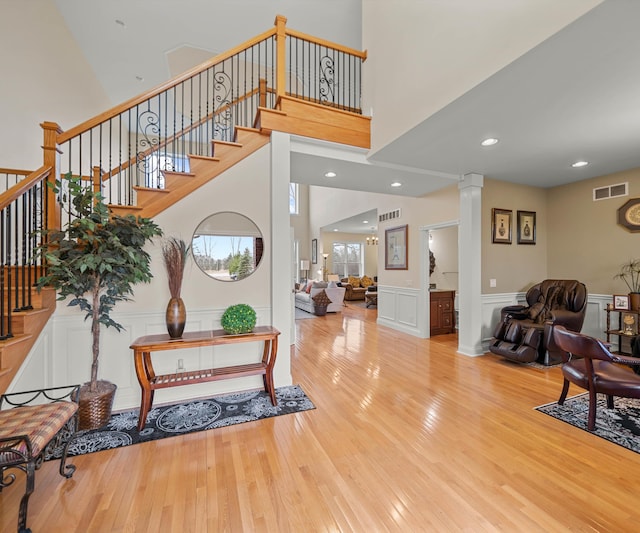 foyer featuring visible vents, hardwood / wood-style floors, stairs, and decorative columns