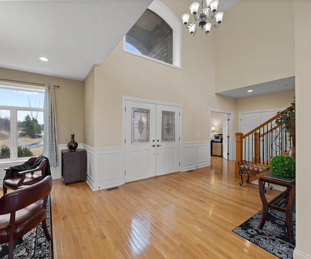 entrance foyer with stairway, visible vents, light wood-style flooring, french doors, and a notable chandelier