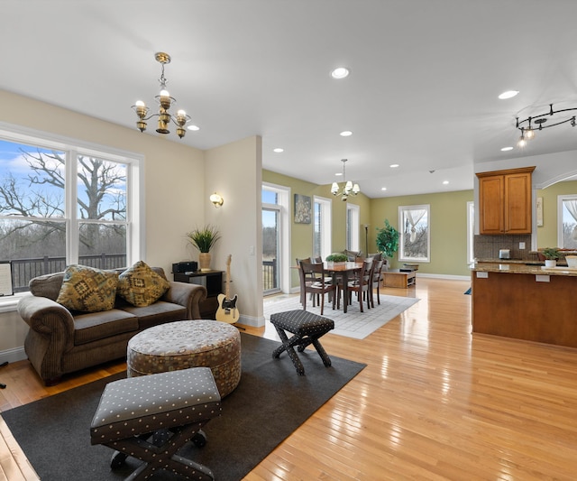 living area featuring a notable chandelier, a healthy amount of sunlight, and light wood-type flooring