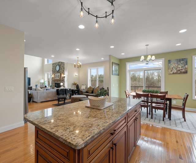 kitchen with brown cabinets, a chandelier, a fireplace, and light wood finished floors