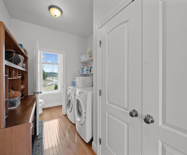 laundry area with laundry area, baseboards, light wood-type flooring, and washer and clothes dryer