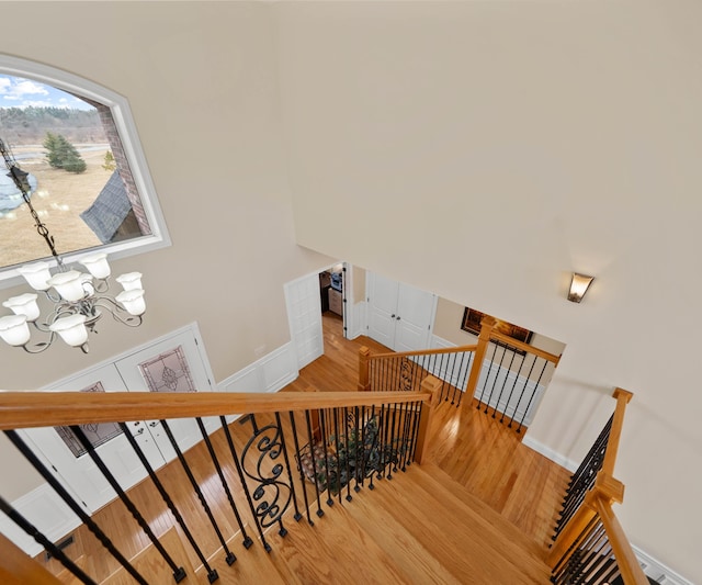 staircase with a notable chandelier, baseboards, and wood finished floors