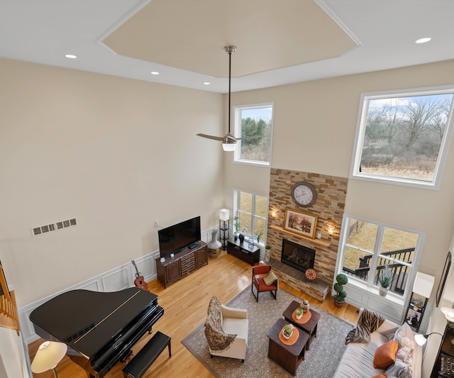 living room featuring wood finished floors, a fireplace, visible vents, and ceiling fan