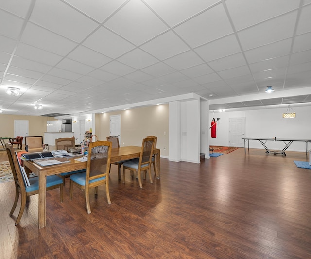 dining area with a paneled ceiling, baseboards, and wood finished floors