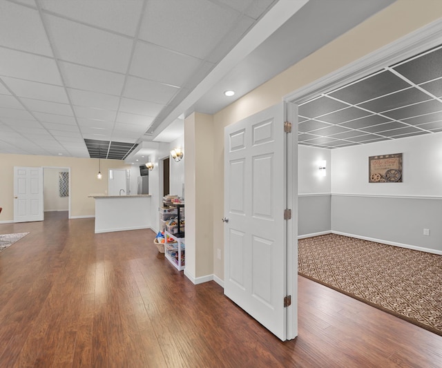 below grade area with hardwood / wood-style floors, a paneled ceiling, and baseboards