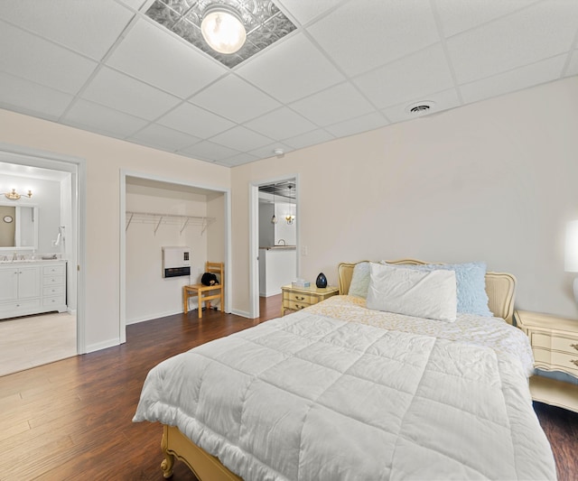 bedroom featuring a sink, wood finished floors, visible vents, and a paneled ceiling