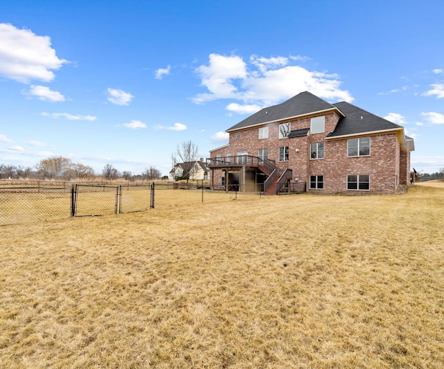 rear view of house with a lawn, a gate, fence, brick siding, and stairs