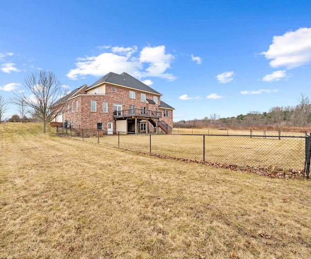 back of house with stairs, a yard, a fenced backyard, and brick siding