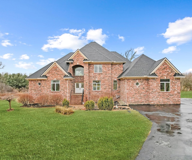 traditional home with brick siding, a shingled roof, and a front lawn