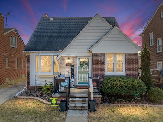 view of front of home featuring brick siding and roof with shingles