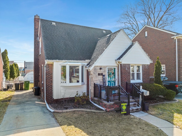 view of front of house with stone siding, brick siding, roof with shingles, and a chimney