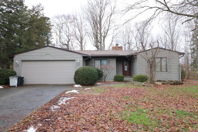 ranch-style home with concrete driveway, a garage, and a chimney