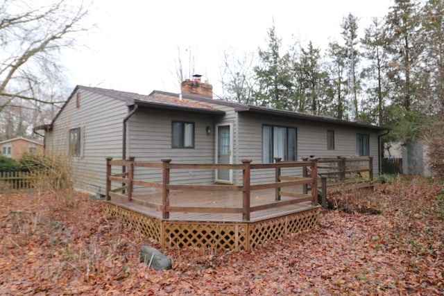 rear view of house featuring a chimney and a deck