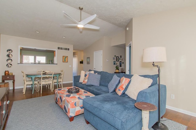 living room featuring wood finished floors, visible vents, baseboards, ceiling fan, and vaulted ceiling