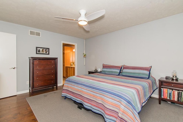 bedroom with visible vents, a textured ceiling, wood finished floors, baseboards, and ceiling fan