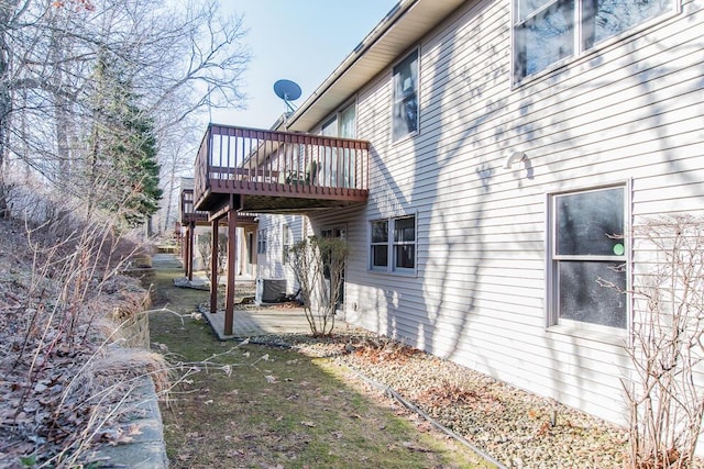 view of property exterior with a wooden deck, a patio, and central AC unit