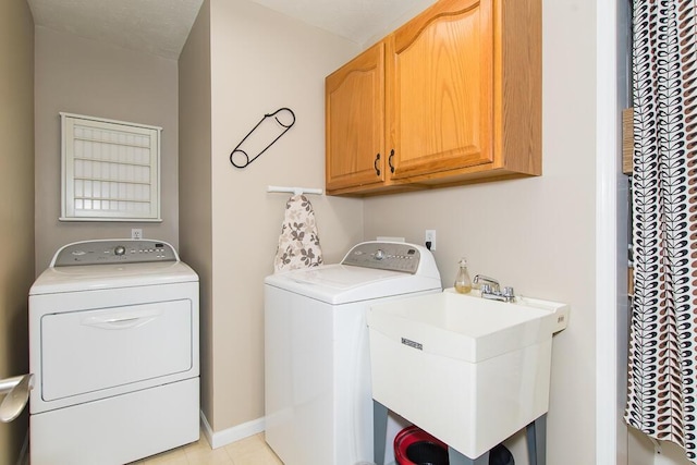 clothes washing area featuring washing machine and clothes dryer, cabinet space, baseboards, and a sink