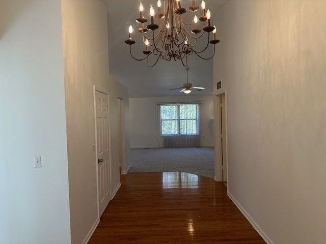 hallway with visible vents, baseboards, and wood finished floors