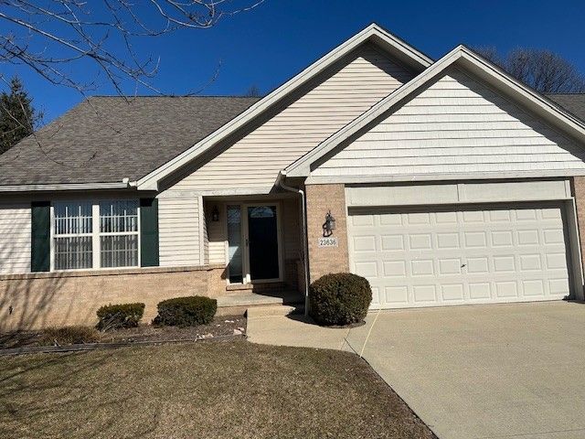 ranch-style home with concrete driveway, an attached garage, and a shingled roof