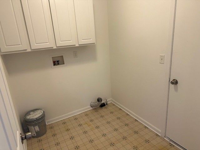 clothes washing area with washer hookup, cabinet space, baseboards, and light floors