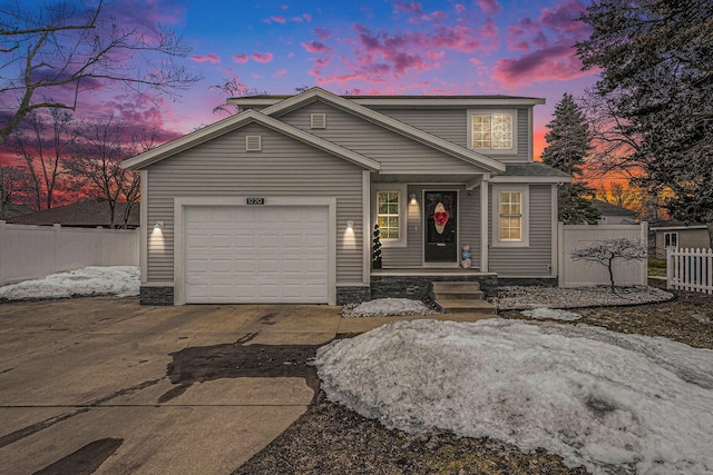 traditional-style home with an attached garage, concrete driveway, and fence