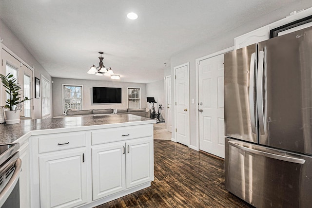 kitchen featuring dark wood-type flooring, open floor plan, white cabinetry, appliances with stainless steel finishes, and a chandelier