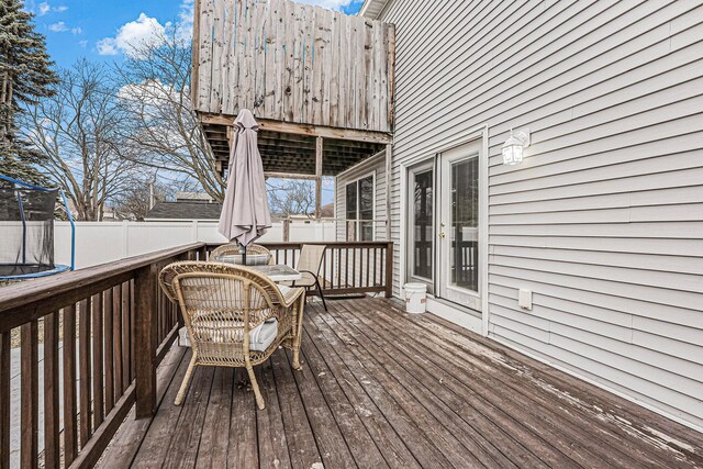 deck with a trampoline and fence