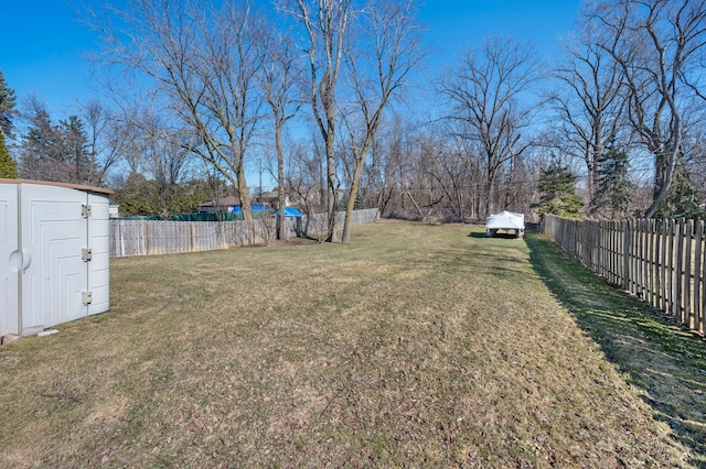 view of yard featuring an outbuilding, a storage unit, and a fenced backyard