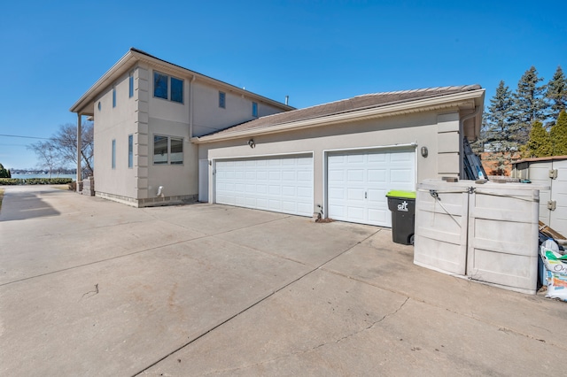 exterior space with concrete driveway, an attached garage, and stucco siding