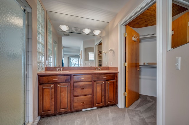 bathroom with double vanity, a shower with shower door, visible vents, and a sink