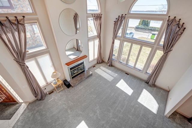 carpeted living area featuring a towering ceiling and a tile fireplace