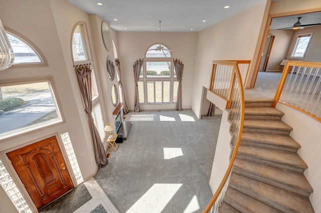 foyer entrance featuring recessed lighting, a high ceiling, stairs, and carpet flooring