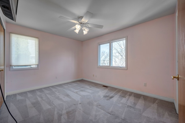 unfurnished room with visible vents, light colored carpet, a ceiling fan, and baseboards