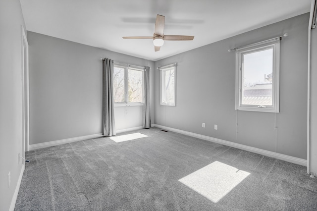 carpeted empty room with visible vents, baseboards, and a ceiling fan