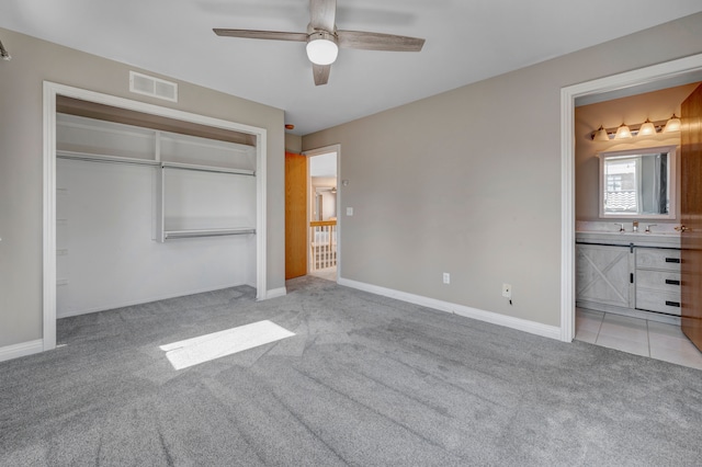 unfurnished bedroom featuring visible vents, a sink, ensuite bath, a closet, and light colored carpet