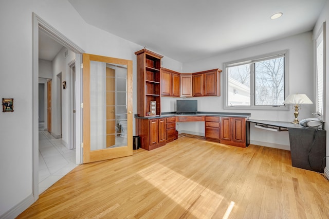 unfurnished office with built in desk, recessed lighting, light wood-type flooring, and baseboards