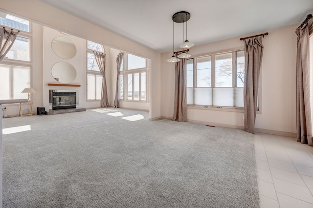 unfurnished living room with a glass covered fireplace, tile patterned floors, carpet flooring, and baseboards