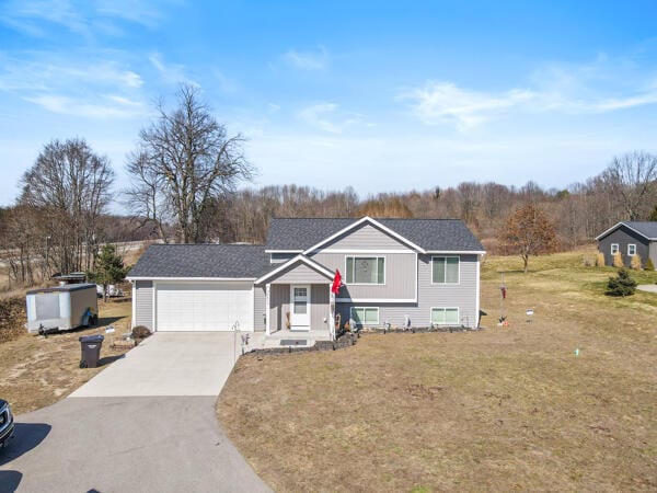 view of front of house featuring a front lawn, an attached garage, and driveway