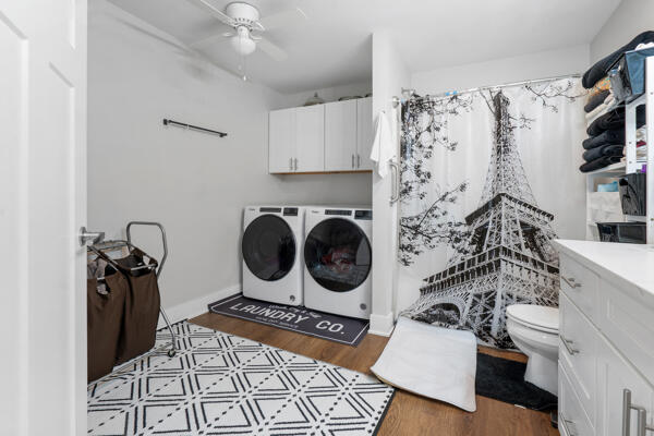 clothes washing area with ceiling fan, separate washer and dryer, wood finished floors, and laundry area