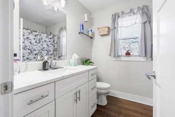 bathroom featuring toilet, curtained shower, wood finished floors, baseboards, and vanity